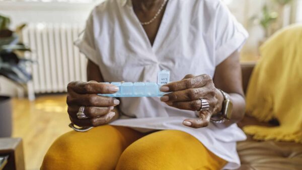 A patient takes medicine out of a daily pill box.