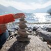person stacking rocks by the lake
