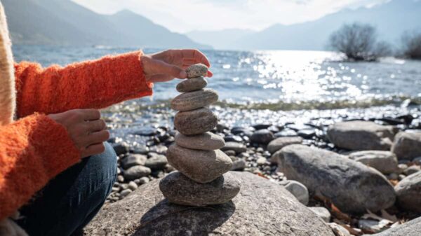 person stacking rocks by the lake