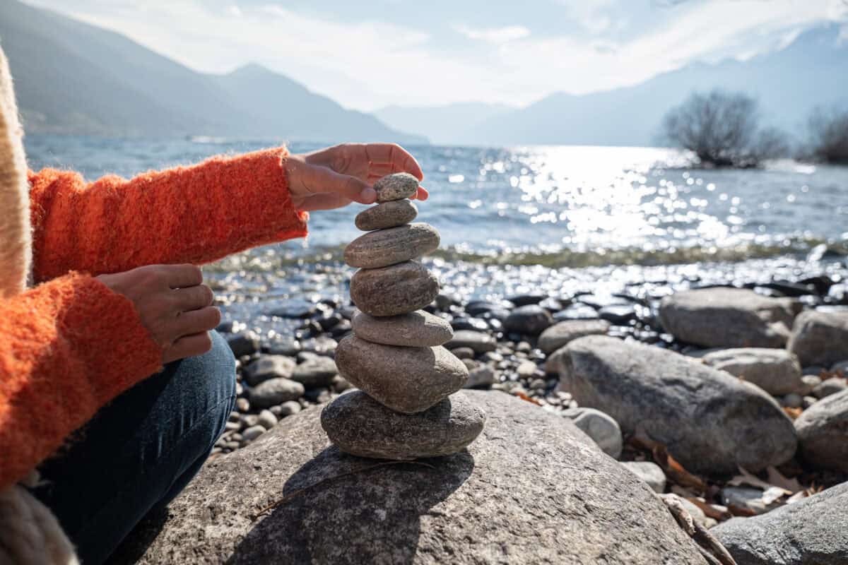 person stacking rocks by the lake