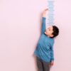 Child measures his height on wall. He is growing taller.