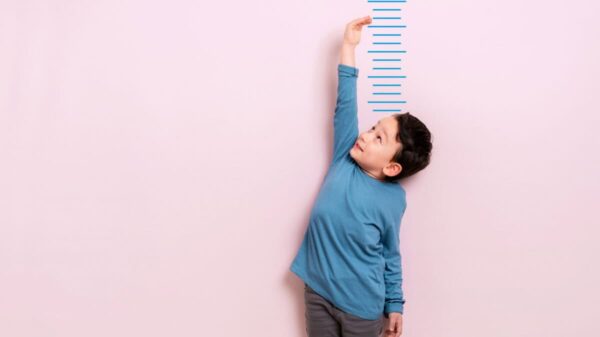 Child measures his height on wall. He is growing taller.
