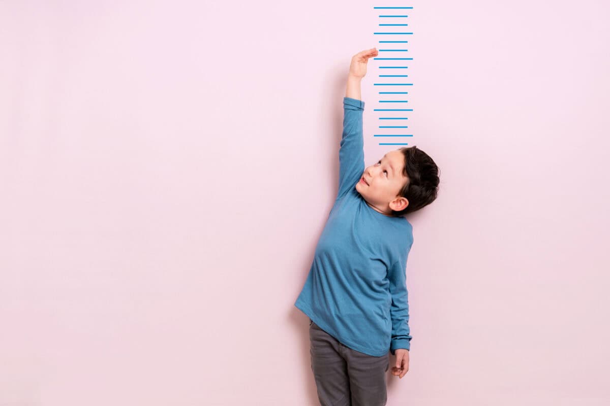 Child measures his height on wall. He is growing taller.